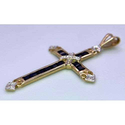 479 - A 9 K yellow gold cross with sapphires and diamonds. Length (with bail): 35 mm, weight: 1.3 g.