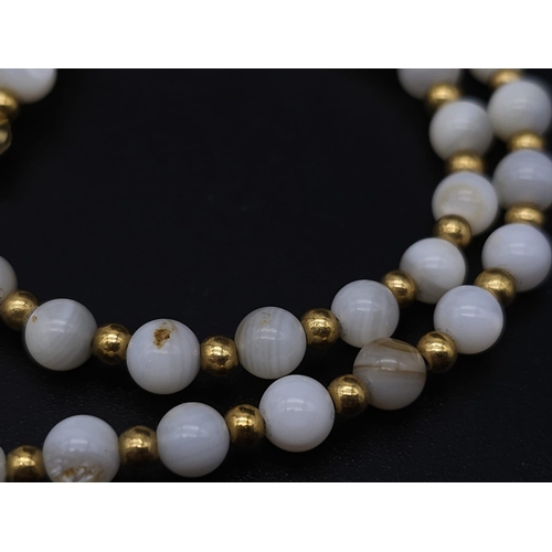 713 - A VERY ATTRACTIVE CHOKER NECKLACE WITH WHITE MARBLEISED BEADS AND GOLD PLATED SPACERS .    13.2gms  ... 