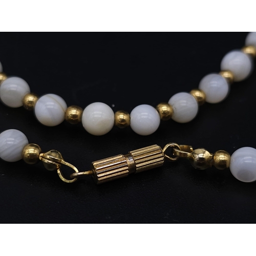 713 - A VERY ATTRACTIVE CHOKER NECKLACE WITH WHITE MARBLEISED BEADS AND GOLD PLATED SPACERS .    13.2gms  ... 