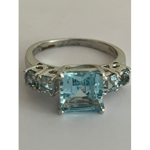 499 - Stunning BLUE TOPAZ and SILVER RING. Having square cut TOPAZ set to top flanked with BLUE TOPAZ Shou... 