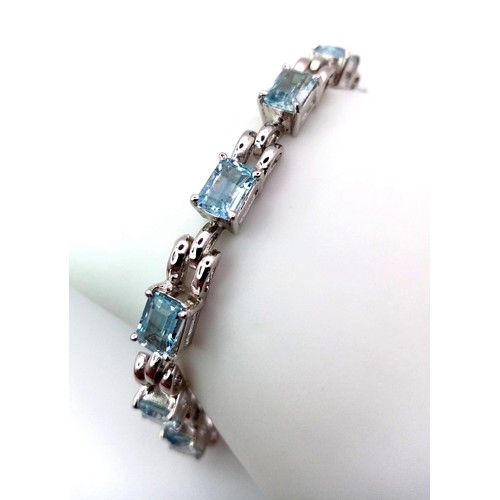 1551 - A Blue Topaz Tennis Bracelet. Rectangular cuts of ice blue topaz set in 925 silver. 19cm. 17.2g tota... 