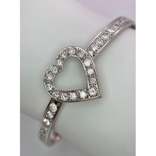 232 - An 18K White Gold and Diamond Heart Bangle. Central diamond round cut heart with diamonds on wings. ... 