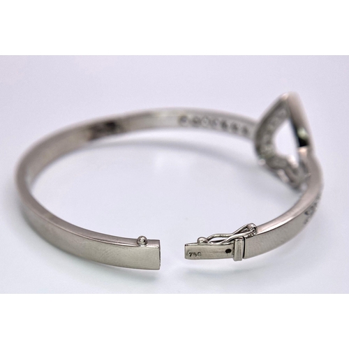 232 - An 18K White Gold and Diamond Heart Bangle. Central diamond round cut heart with diamonds on wings. ... 