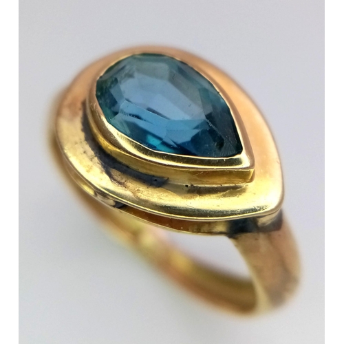 288 - An 18K Yellow Gold Blue Gemstone (possibly topaz) Ring. Pear shaped stone set within a raised founda... 