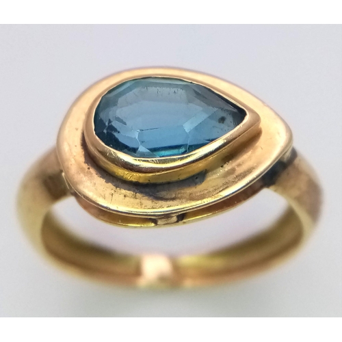 288 - An 18K Yellow Gold Blue Gemstone (possibly topaz) Ring. Pear shaped stone set within a raised founda... 