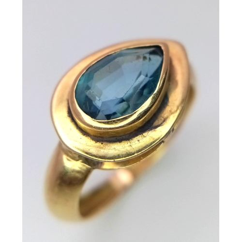 288 - An 18K Yellow Gold Blue Gemstone (possibly topaz) Ring. Pear shaped stone set within a raised founda... 