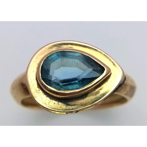 288 - An 18K Yellow Gold Blue Gemstone (possibly topaz) Ring. Pear shaped stone set within a raised founda... 