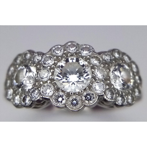 305 - An 18K White Gold Triple Cluster Diamond Ring. Central brilliant round cut diamond with diamond halo... 