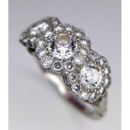 305 - An 18K White Gold Triple Cluster Diamond Ring. Central brilliant round cut diamond with diamond halo... 