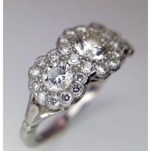 305 - An 18K White Gold Triple Cluster Diamond Ring. Central brilliant round cut diamond with diamond halo... 