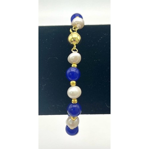 884 - A Cultured Pearl and Lapis Lazuli Bracelet. Gilded spacers and clasp. 16cm.