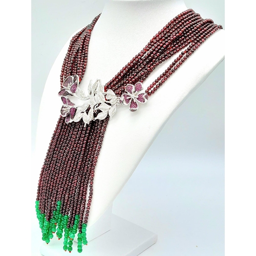 182 - A statement necklace consisting of eleven strands of round garnets with a spectacular central floral... 