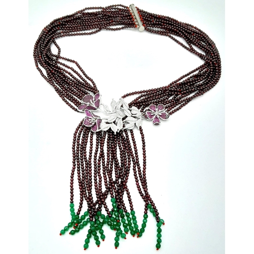 182 - A statement necklace consisting of eleven strands of round garnets with a spectacular central floral... 