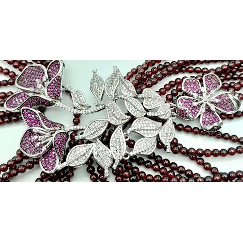 182 - A statement necklace consisting of eleven strands of round garnets with a spectacular central floral... 