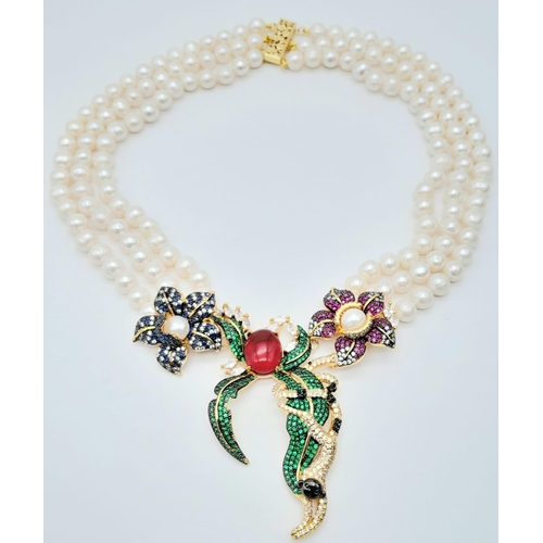 217 - A show stopping three strand natural pearl necklace with a substantial multi gem central pendant par... 