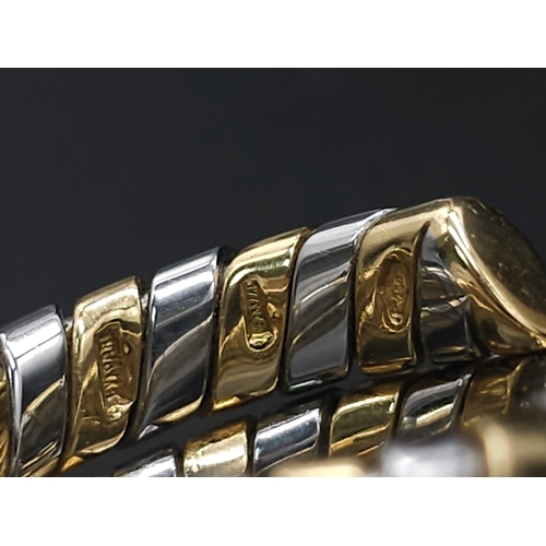 23 - A Bulgari Tubogas Flexible 18K Gold Ring. 16 yellow gold pipe bands alternate with stainless steel b... 