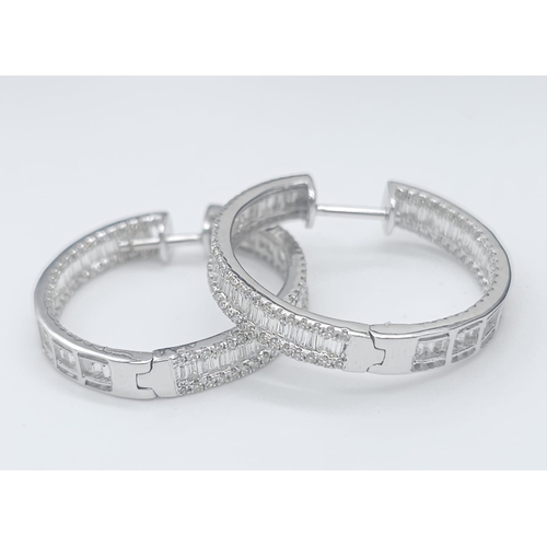 43 - A Pair of 18K White Gold 2ctw Diamond Hoop Earrings. An exquisite combination of baguette and round ... 