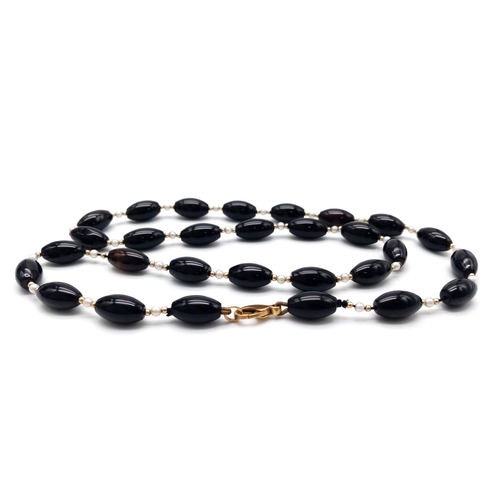 520 - A Onyx, Pearl & Gold Beaded Necklace with a 9kt Yellow Gold Clasp.
Measuring 58cm in length, this st... 