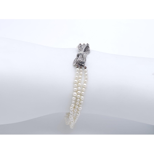 527 - A Triple Strand Fresh Pearl Bracelet with a 18kt White Gold, Diamond Set Bow Clasp.
Measuring 12cm i... 