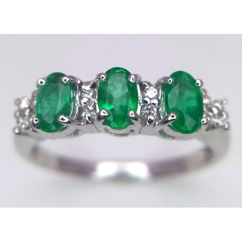 698 - An 18K White Gold Emerald and Diamond Ring. Three oval emeralds with 12 round cut diamond accents. S... 