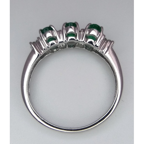 698 - An 18K White Gold Emerald and Diamond Ring. Three oval emeralds with 12 round cut diamond accents. S... 