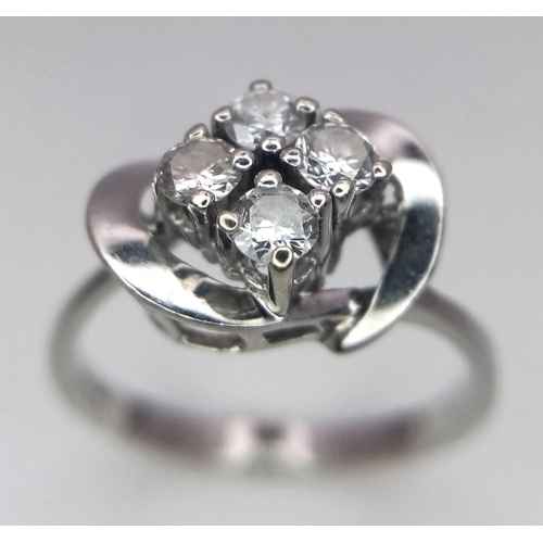 719 - An 18K White Gold Four Stone Diamond Ring. Four brilliant round cut diamonds in a swirl setting. 1ct... 