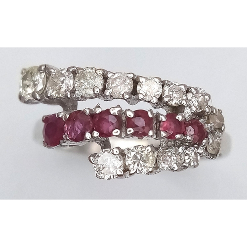 268 - An 18K White Gold Ruby and Diamond Crossover Ring. Six round cut rubies in-between two rows of round... 