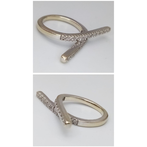 338 - An 18K White Gold (tested) and Diamond 'Forever' Crossover Ring. Size I. 4.52g total weight.