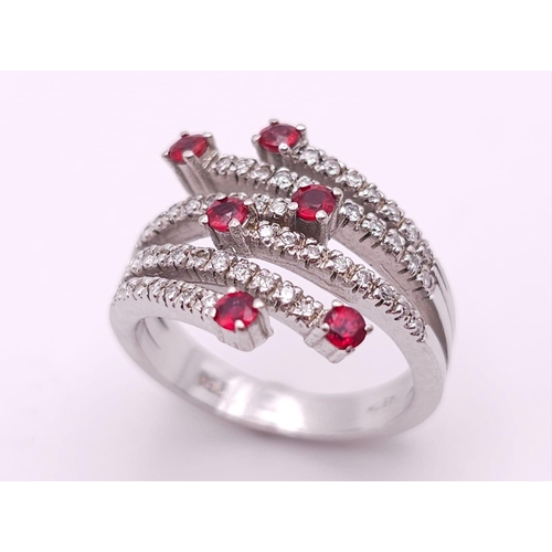 64 - An 18K White Gold, Ruby and Diamond Five-Stem Swirl Ring. 
Size M. 7.1g total weight.