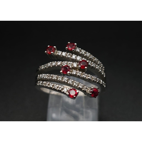 64 - An 18K White Gold, Ruby and Diamond Five-Stem Swirl Ring. 
Size M. 7.1g total weight.