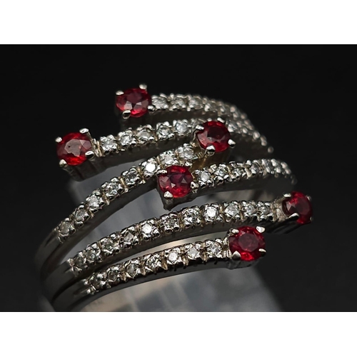 64 - An 18K White Gold, Ruby and Diamond Five-Stem Swirl Ring. 
Size M. 7.1g total weight.