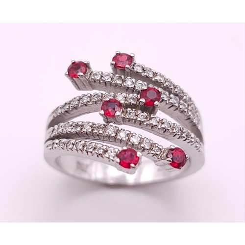 64 - An 18K White Gold, Ruby and Diamond Five-Stem Swirl Ring. 
Size M. 7.1g total weight.