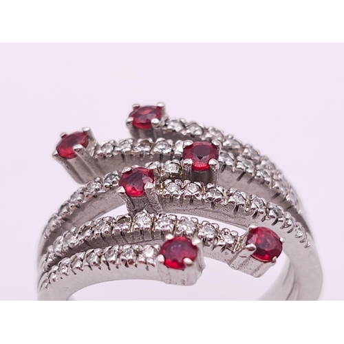 64 - An 18K White Gold, Ruby and Diamond Five-Stem Swirl Ring. 
Size M. 7.1g total weight.