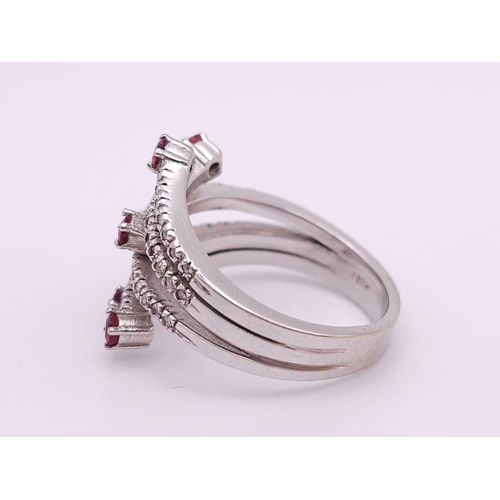 64 - An 18K White Gold, Ruby and Diamond Five-Stem Swirl Ring. 
Size M. 7.1g total weight.