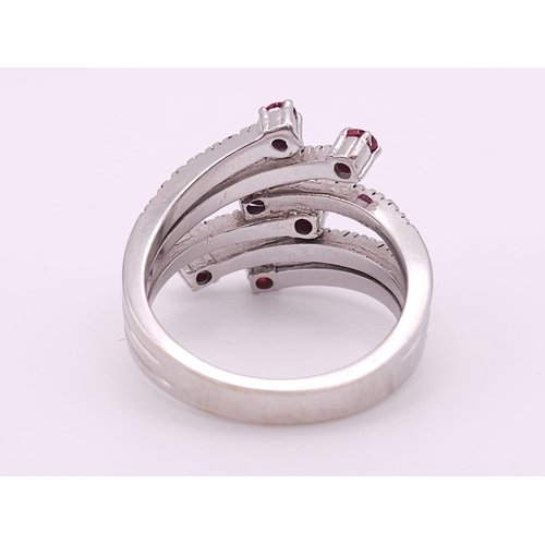 64 - An 18K White Gold, Ruby and Diamond Five-Stem Swirl Ring. 
Size M. 7.1g total weight.