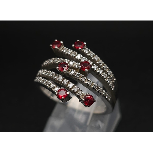 64 - An 18K White Gold, Ruby and Diamond Five-Stem Swirl Ring. 
Size M. 7.1g total weight.