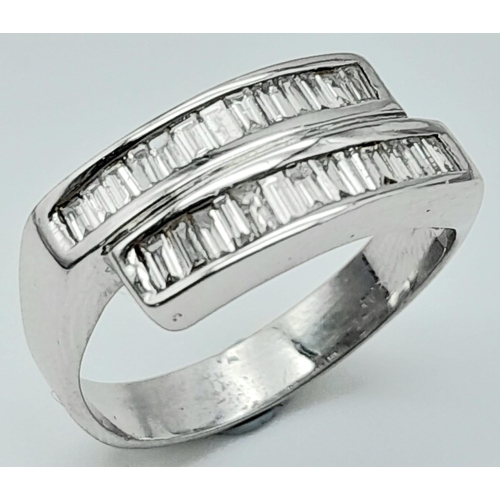 1339 - An 18K White Gold Diamond Crossover Ring. 24 small baguette cut diamonds in a crossover formation. S... 