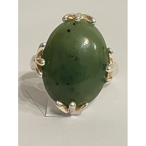 693 - SILVER and GREEN NEPHRITE RING. Consisting a large polished oval NEPHRITE Set in a Designer four cla... 