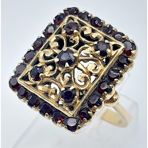 522 - A showstopper, 18KT Yellow Gold, Garnet Set Ring.
A stunningly unique, gold & stone interlacing desi... 