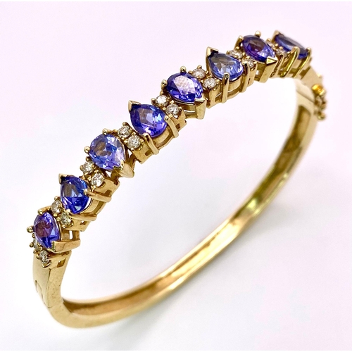 9 - An Alluring 14K Yellow Gold, Amethyst and Diamond Bangle. 
High-grade, clean pear-cut amethysts sepa... 