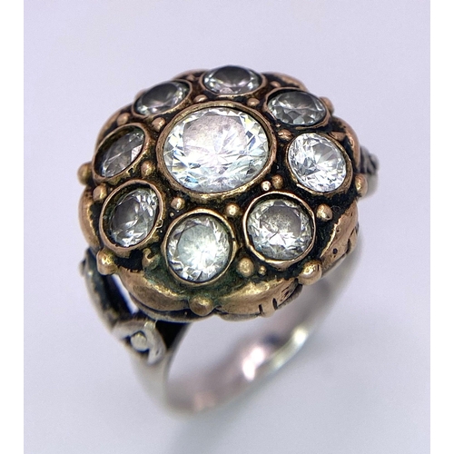 1417 - A 925 Silver Ring, with a fancy circular design adorned with white stones and interlaced with gold t... 