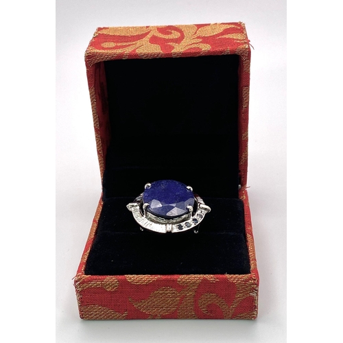 2893 - A Blue Sapphire and 925 Silver Ring. 13.90g. Size P. 14g total weight. Comes with a presentation cas... 