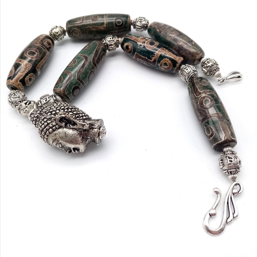 54 - A Tibetan treasure: a nine eyed, large DZI beaded necklace and earrings set with a young Buddha head... 