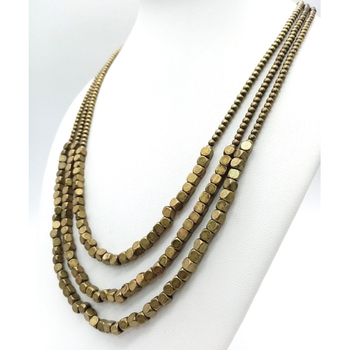 835 - A Collection of Bronzed, Gold tone Jewellery.
Featuring a triple strand, metallic beaded necklace, m... 