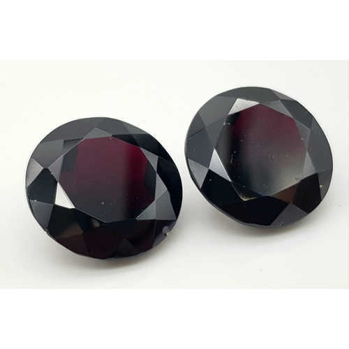 1114 - A Pair of 67.32ct Round Brilliant Shaped Dark Red Garnets. 20mm. AIG Milan Certified.