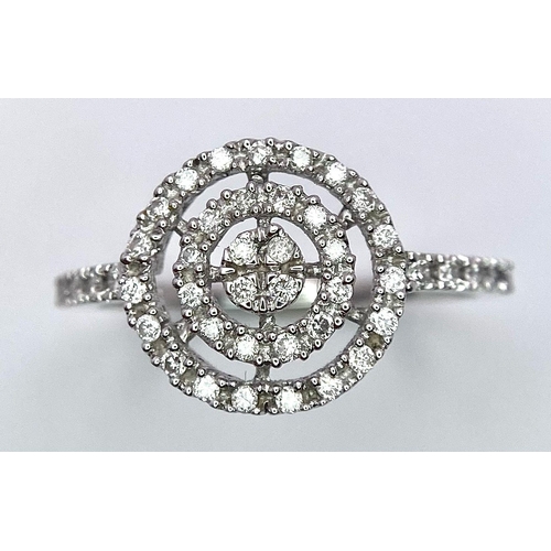 376 - An 18K White Gold Diamond Target Ring. A pave set diamond bullseye with diamond wings. Size M/N. 1.9... 