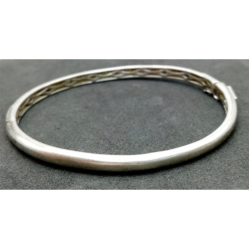 202 - A vintage 925 silver stone set click-on bangle. Total weight 12.15G. Widest inner length 7cm. Please... 