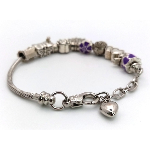 708 - A tested sterling silver bracelet with ten silver charms, total weight:  30.9 g.