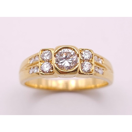 618 - An 18K Yellow Gold and Diamond Ring. A High grade central bright round cut diamond with 12 further d... 