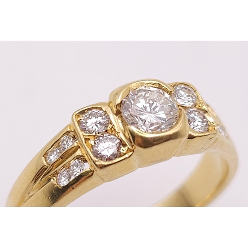 618 - An 18K Yellow Gold and Diamond Ring. A High grade central bright round cut diamond with 12 further d... 